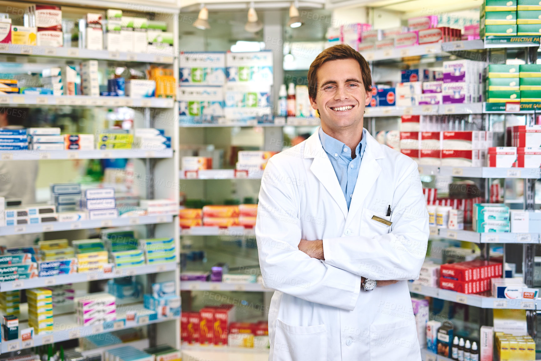 Buy stock photo Cropped portrait of a handsome young male pharmacist standing with his arms crossed in the pharmacy