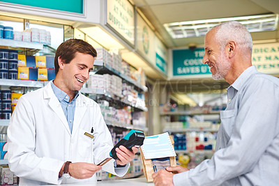 Buy stock photo Cropped shot of a handsome young male pharmacist helping a customer in the pharmacy