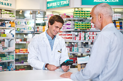 Buy stock photo Cropped shot of a handsome young male pharmacist helping a customer in the pharmacy