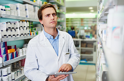 Buy stock photo Shot of a young pharmacist using a digital tablet in a pharmacy