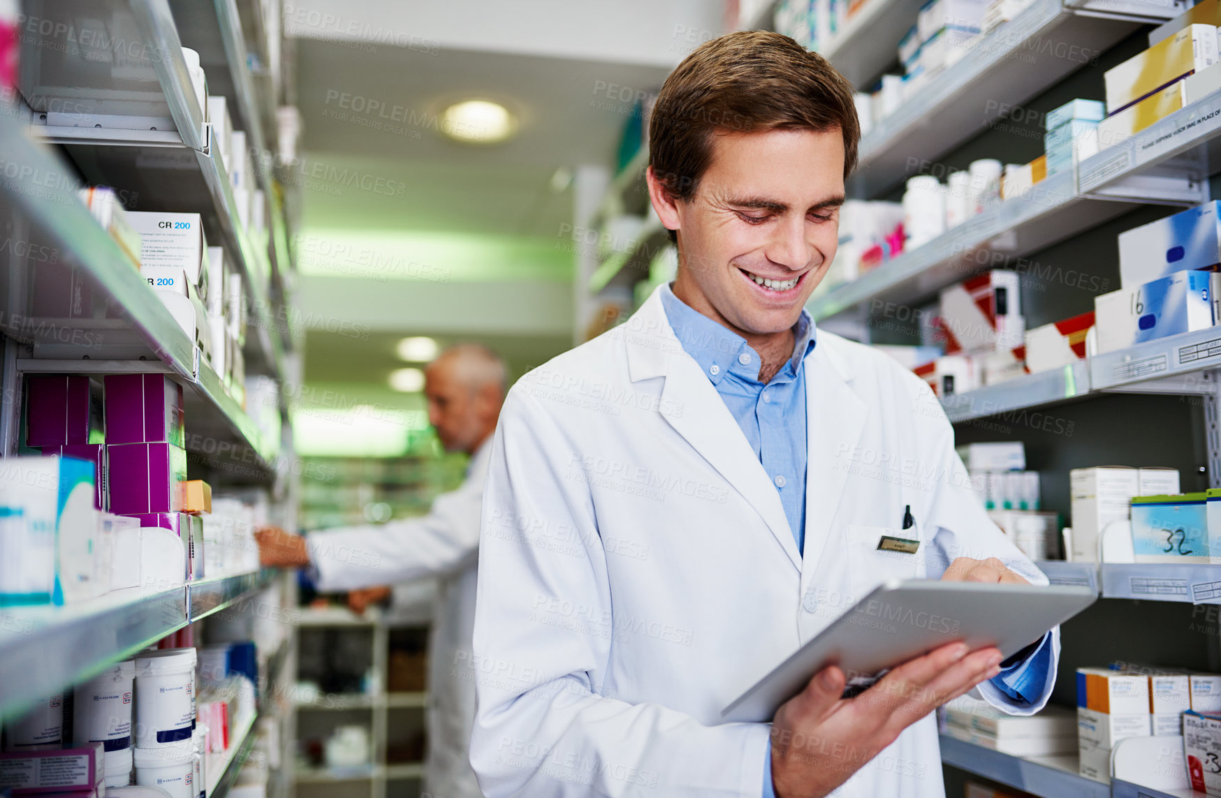 Buy stock photo Shot of a young pharmacist using a digital tablet in a pharmacy