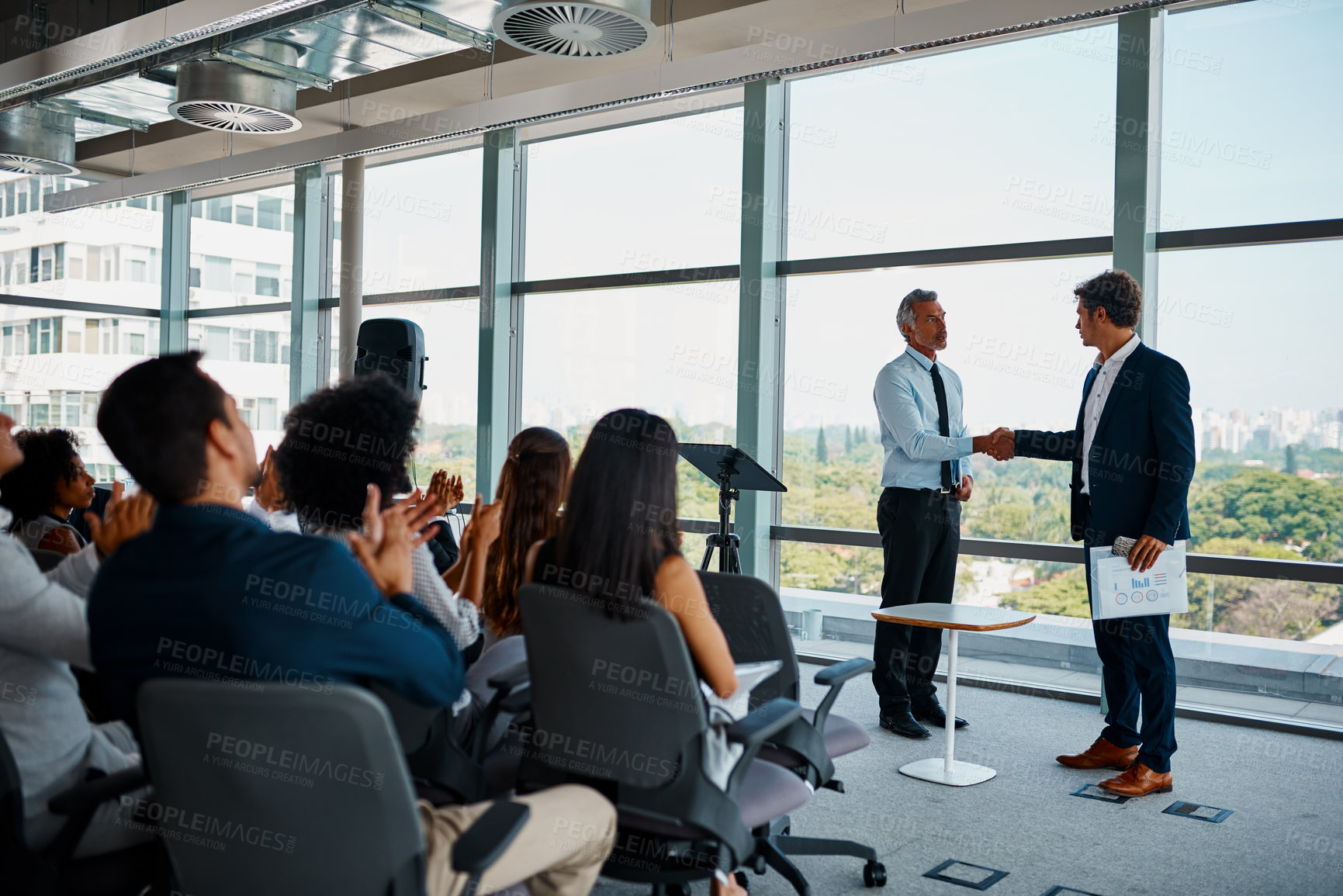 Buy stock photo Full length shot of two businessmen shaking hands in front of an audience during a seminar