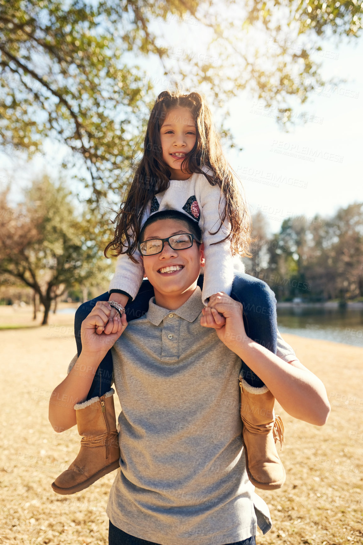 Buy stock photo Cropped shot of a teenage boy carrying his adorable little sister on his shoulders