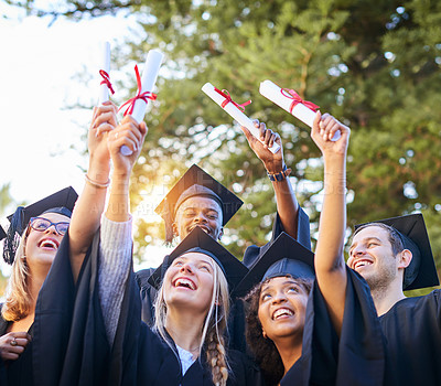 Buy stock photo Shot of a group of graduates holding their diplomas up in the air