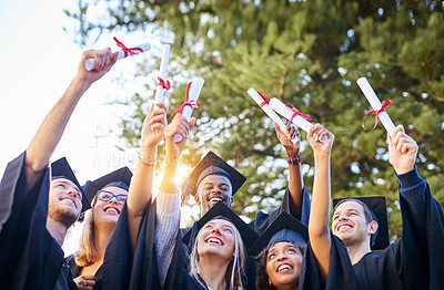 Buy stock photo Shot of a group of graduates holding their diplomas up in the air