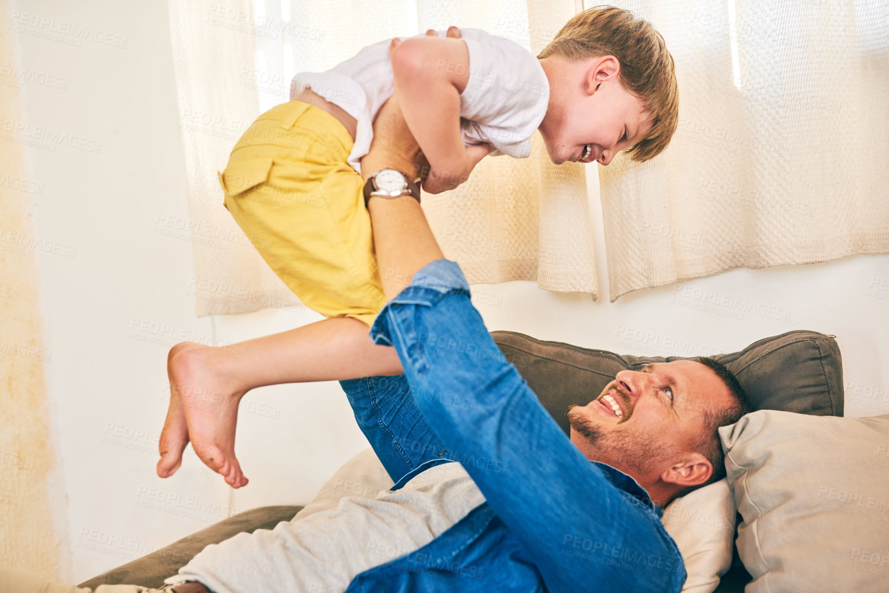 Buy stock photo Shot of a happy little boy having fun with his father at home