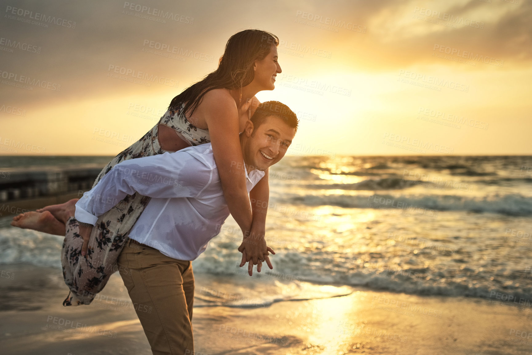 Buy stock photo Cropped portrait of a handsome young man piggybacking his girlfriend on the beach