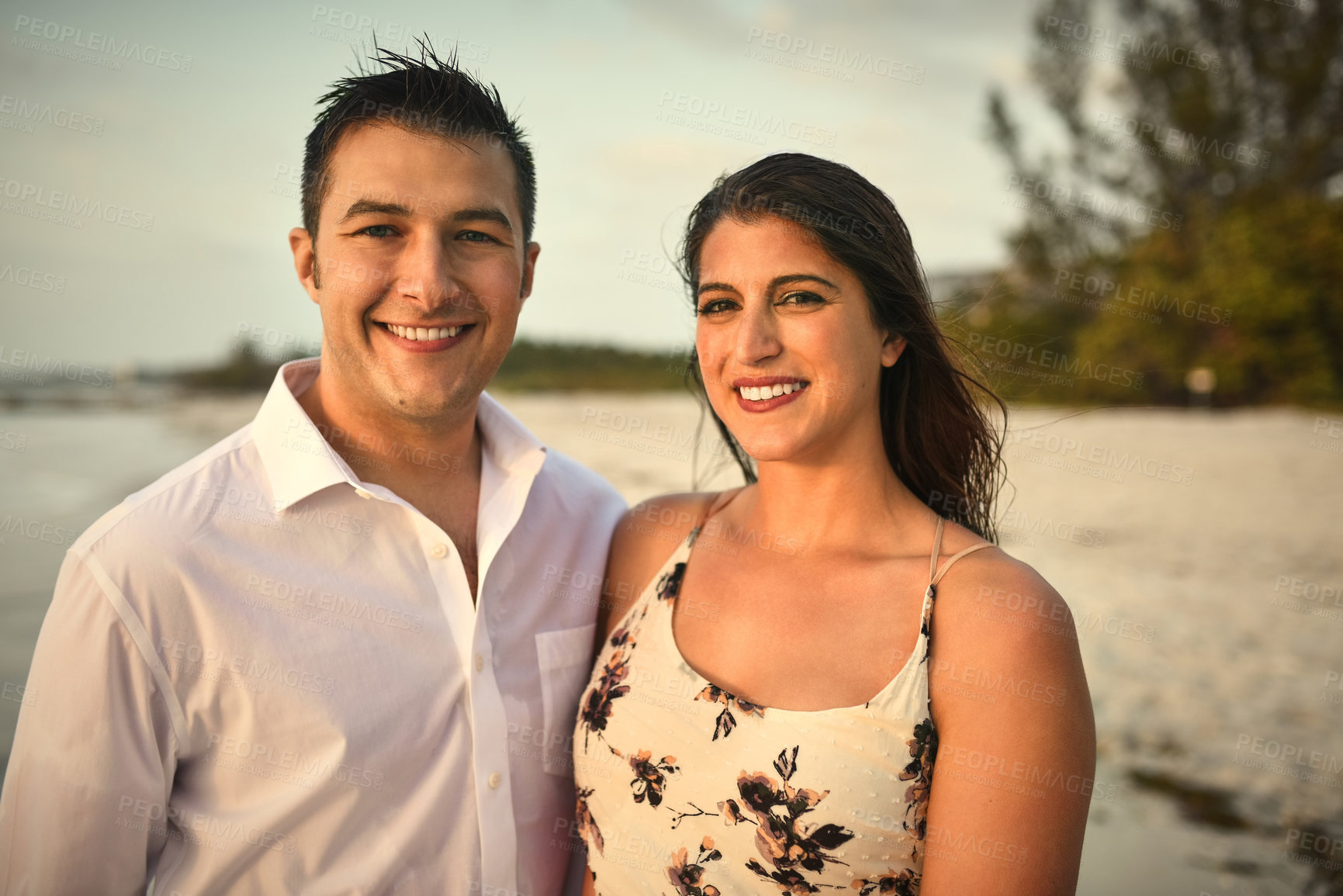 Buy stock photo Cropped portrait of an affectionate young couple standing side by side on the beach