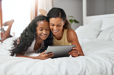 Buy stock photo Shot of a mom and daughter lying on bed with a digital tablet