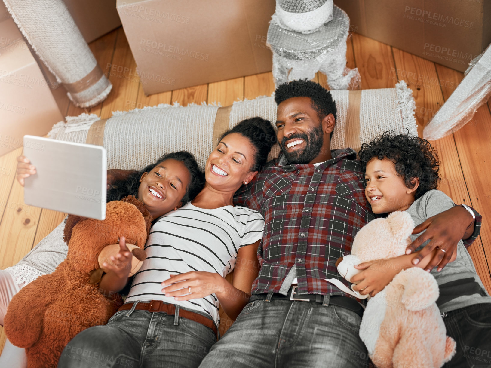 Buy stock photo Shot of a family of four lying together on the floor in their new home