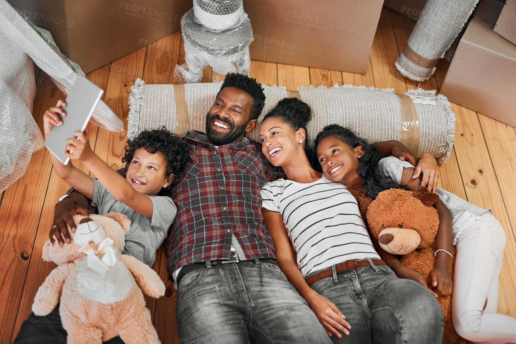 Buy stock photo Shot of a family of four lying together on the floor in their new home