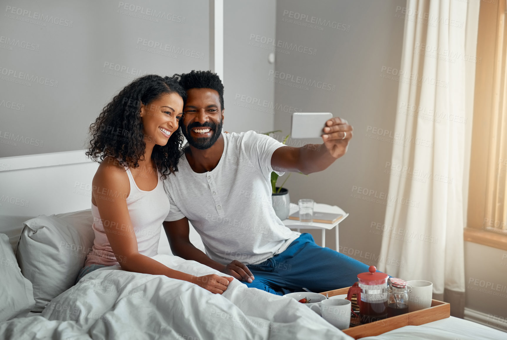 Buy stock photo Cropped shot a young attractive couple taking a selfie while having breakfast in bed at home