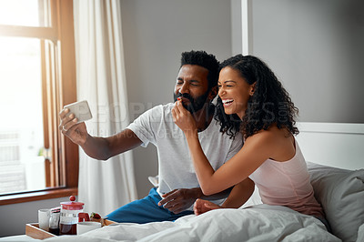 Buy stock photo Cropped shot a young attractive couple taking a selfie while having breakfast in bed at home