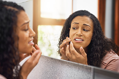 Buy stock photo Cropped shot of an attractive young woman examining her face in a mirror in the bathroom at home