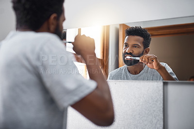 Buy stock photo Cropped shot of a handsome young man brushing his teeth in the bathroom at home