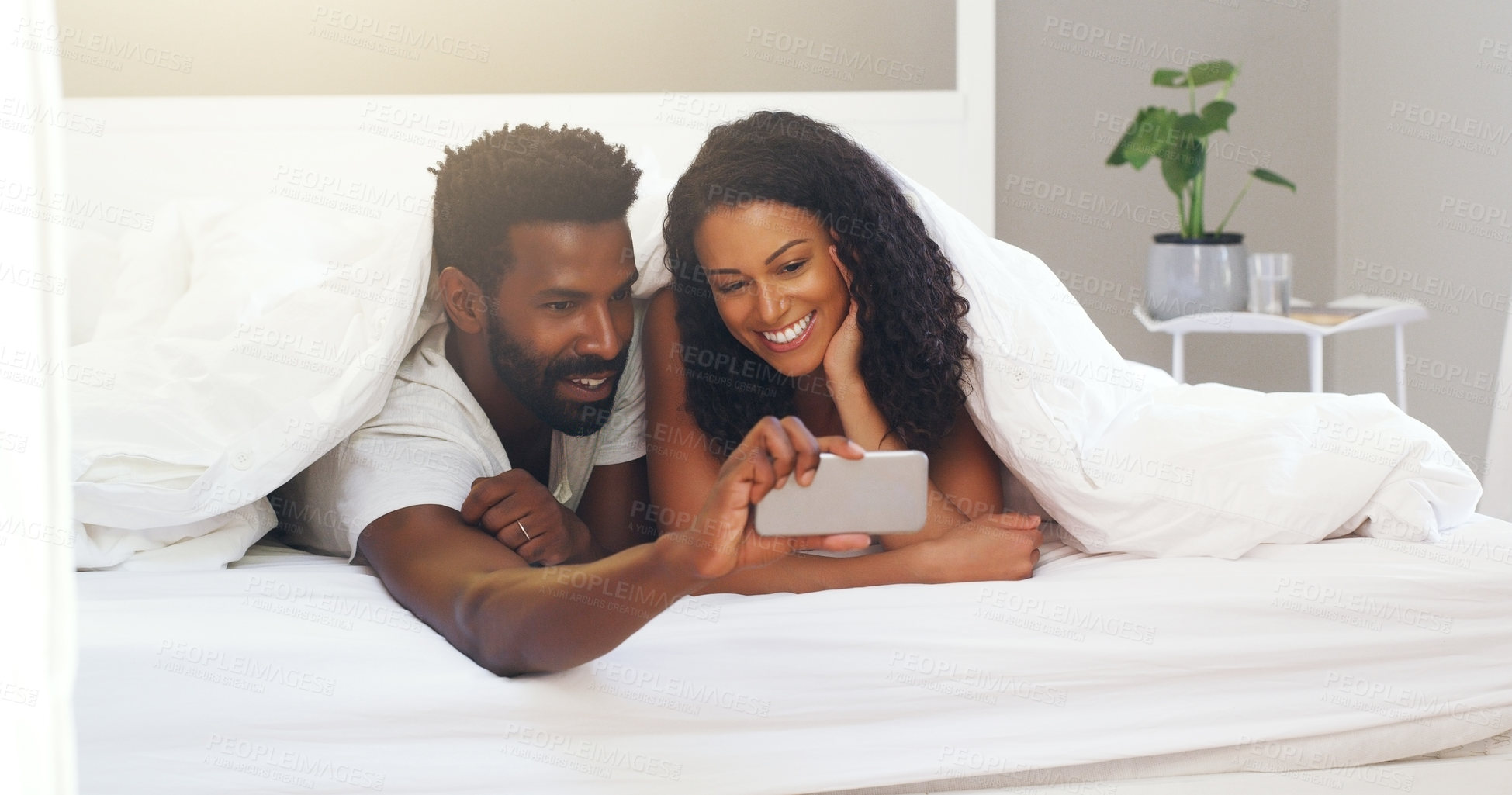 Buy stock photo Cropped shot of a young attractive couple taking a selfie in bed at home