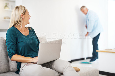 Buy stock photo Woman, home and laptop on sofa thinking, talking and husband sweeping for house maintenance in apartment. Social media, break and supportive married couple or together, helping and happy weekend