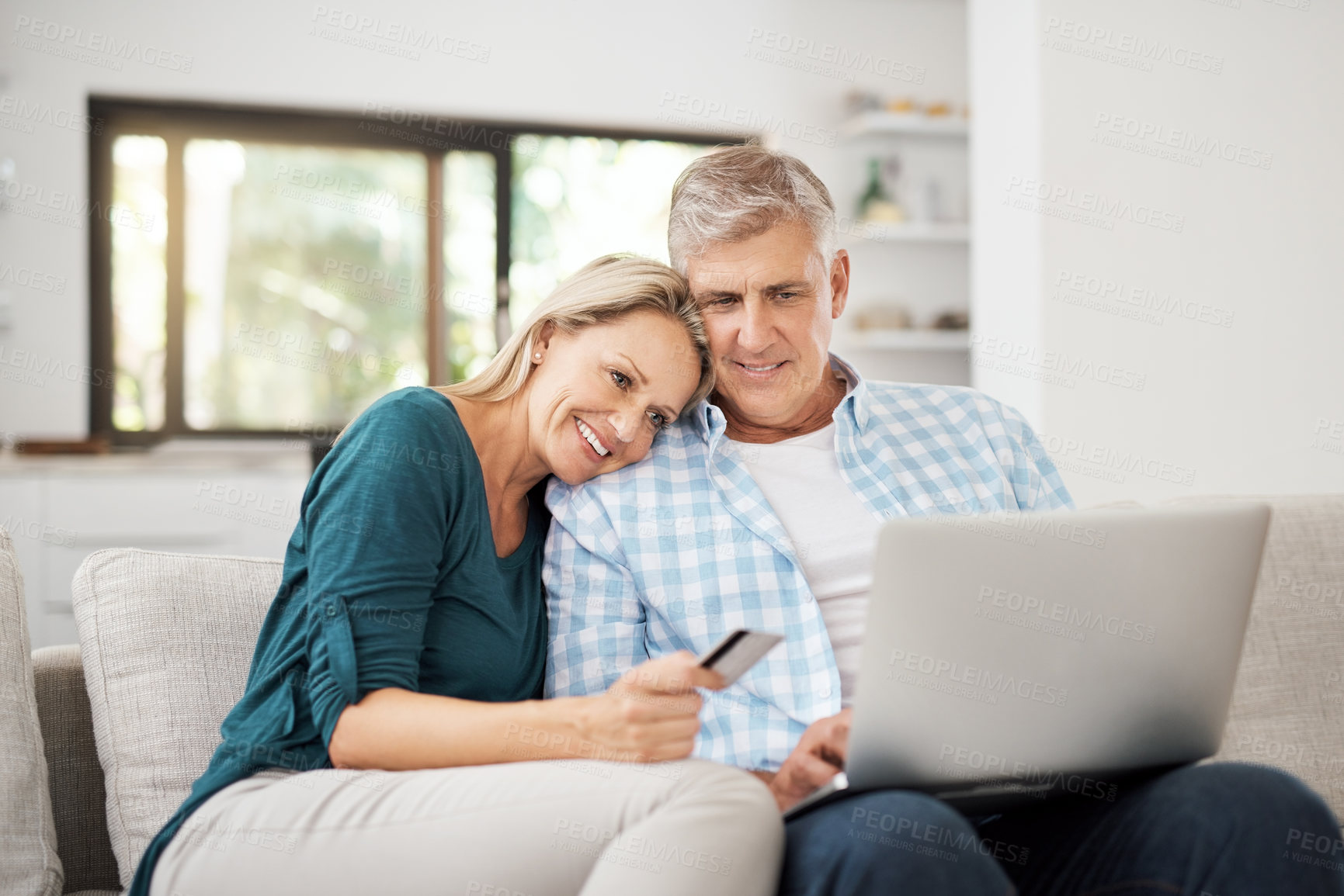 Buy stock photo Cropped shot of an affectionate mature couple using their laptop to do some online shopping at home