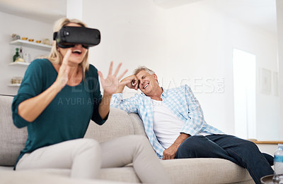 Buy stock photo Cropped shot of a mature woman using a VR headset with her husband in the background