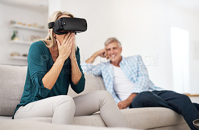 Buy stock photo Cropped shot of a mature woman using a VR headset with her husband in the background