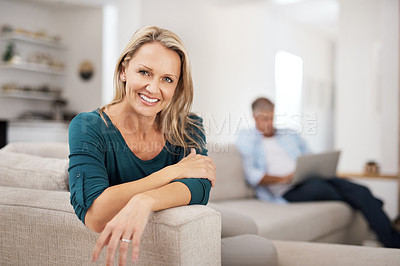 Buy stock photo Portrait of an attractive mature woman relaxing at home with her husband in the background