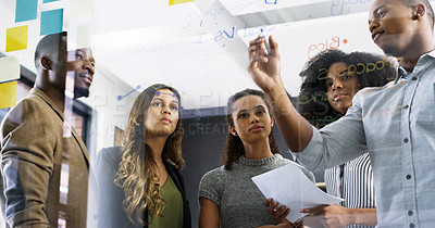 Buy stock photo Cropped shot of a diverse group of businesspeople brainstorming on a glass wall in a modern office
