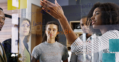 Buy stock photo Cropped shot of a diverse group of businesspeople brainstorming on a glass wall in a modern office