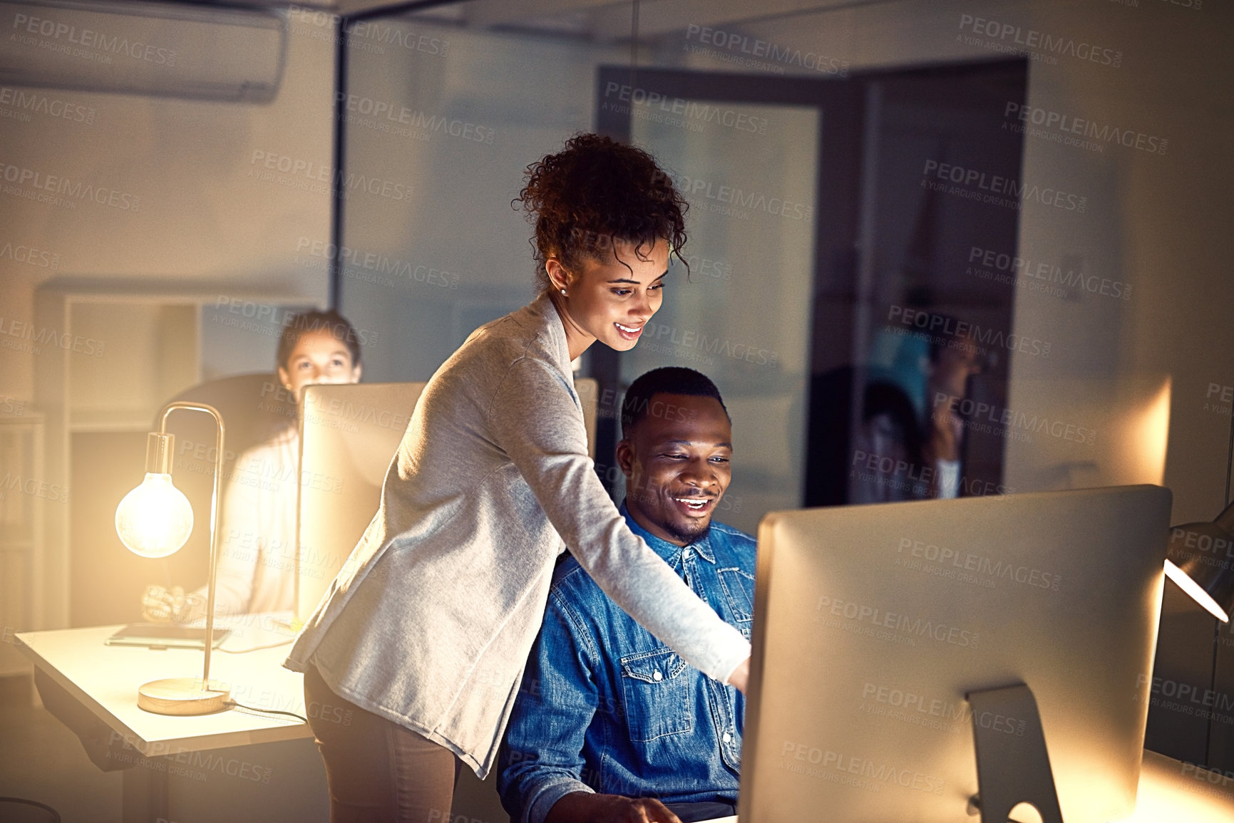 Buy stock photo Shot of two colleagues working late together on a computer in an office