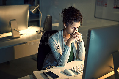 Buy stock photo Shot of a young businesswoman looking stressed out while working late in an office