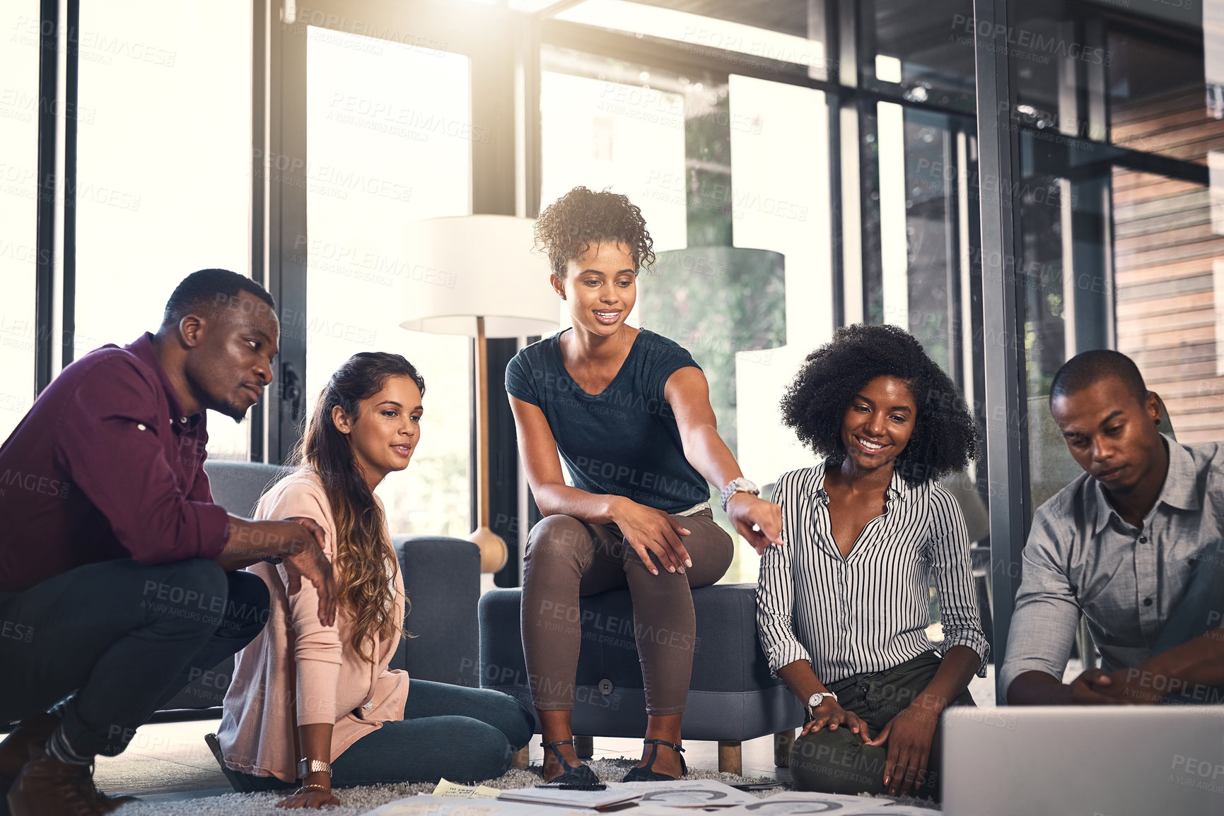 Buy stock photo Shot of a group of young entrepreneurs going through paperwork together in a modern office