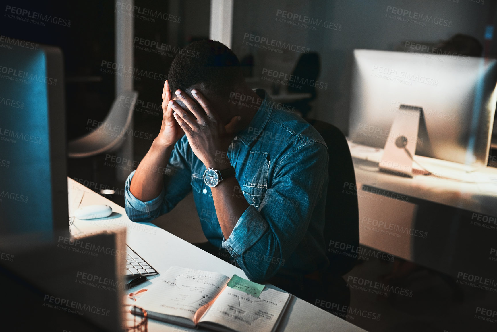 Buy stock photo High angle shot of a young male designer looking stressed while working on his computer in the office