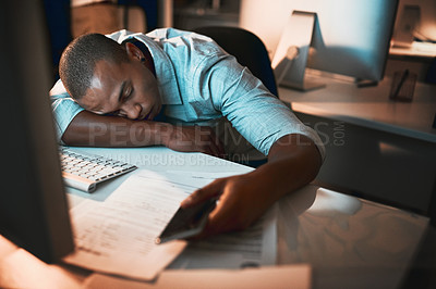Buy stock photo High angle shot of a young male designer sleeping at his desk while working late in the office