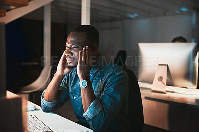 Buy stock photo High angle shot of a young male designer looking stressed while working on his computer in the office