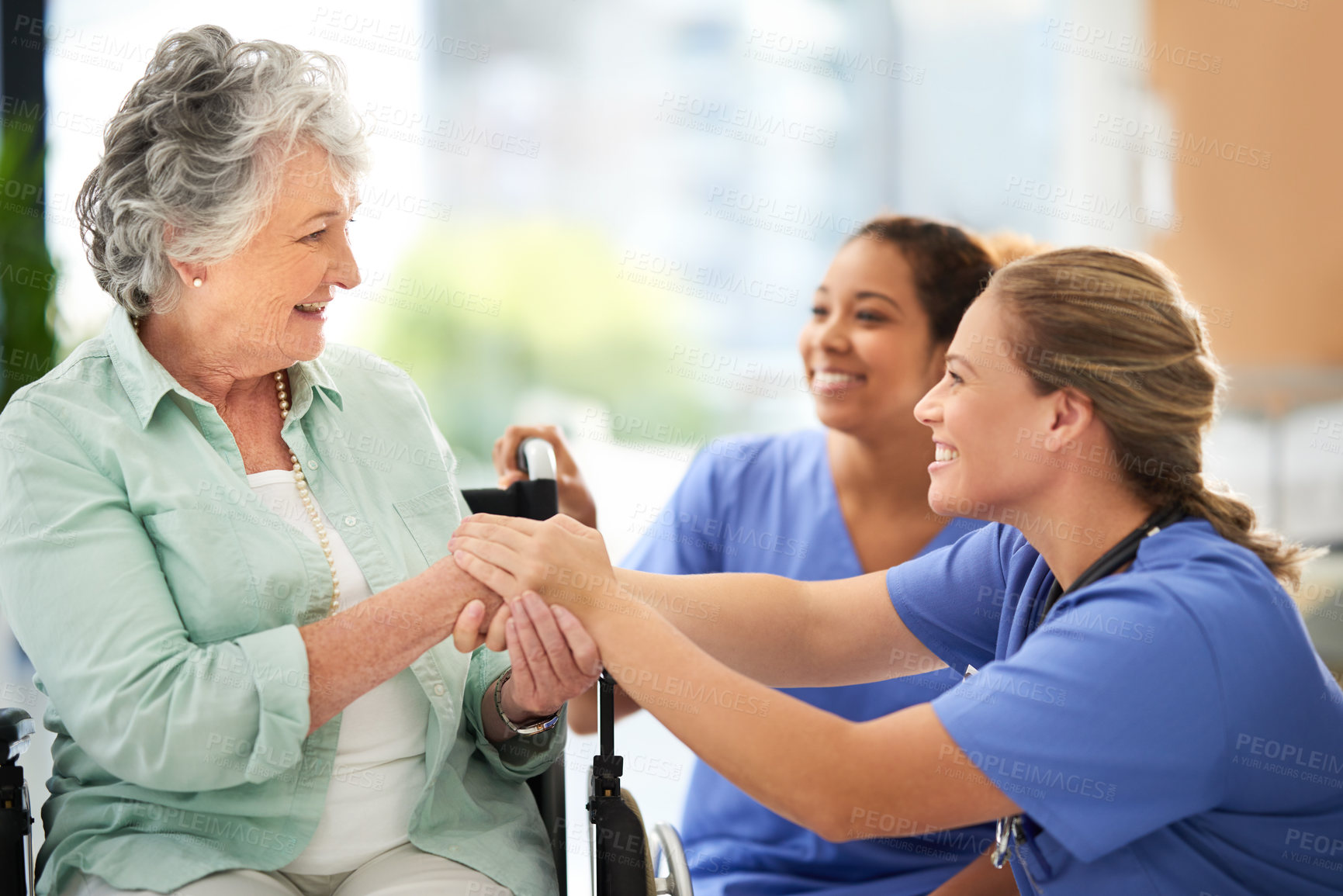 Buy stock photo Cropped shot of two attractive female nurses talking with their wheelchair-bound senior patient in the hospital