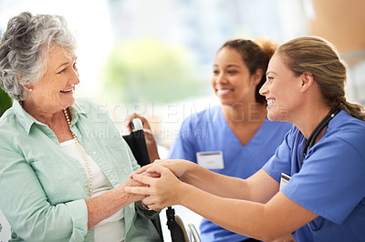 Buy stock photo Cropped shot of two attractive female nurses talking with their wheelchair-bound senior patient in the hospital