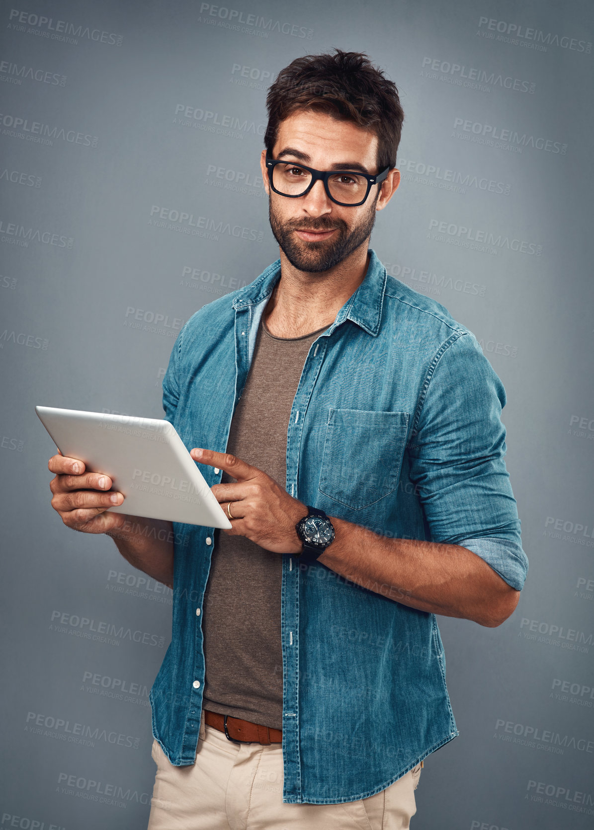Buy stock photo Studio shot of a handsome young man using a digital tablet against a grey background