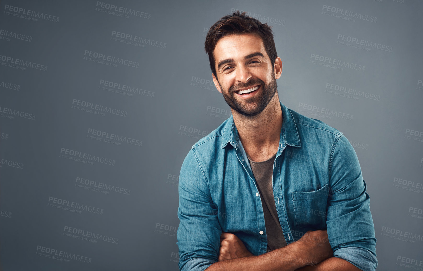 Buy stock photo Studio shot of a handsome and happy young man posing against a grey background