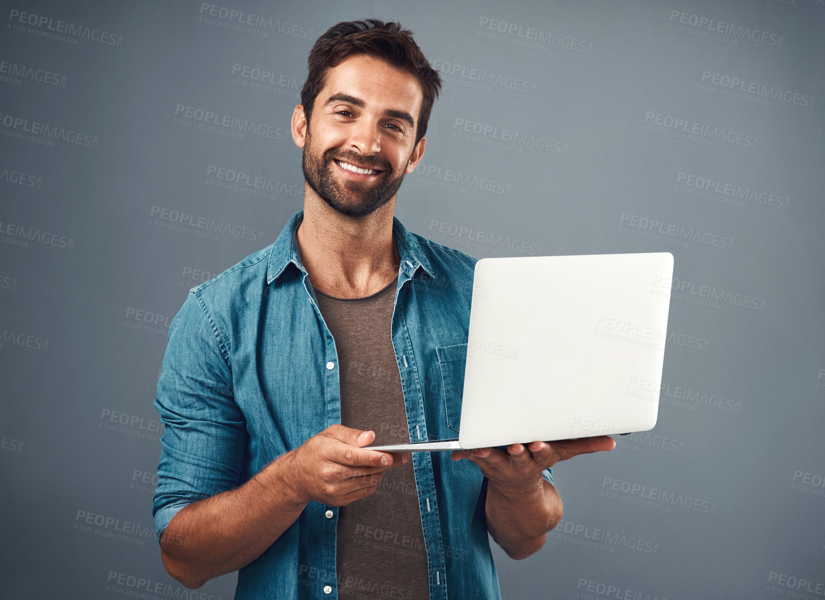 Buy stock photo Studio shot of a handsome young man using a laptop against a grey background