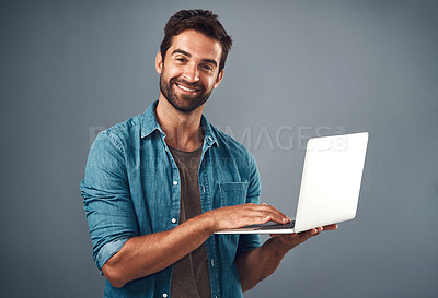 Buy stock photo Studio shot of a handsome young man using a laptop against a grey background