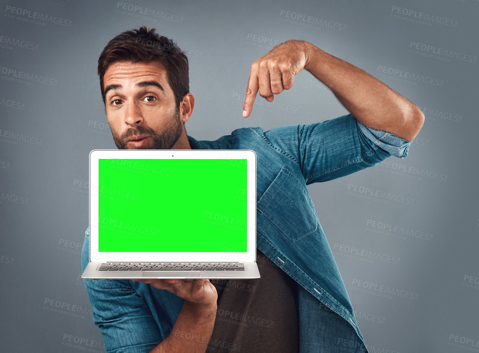 Buy stock photo Man, laptop and pointing on mockup green screen for advertising or marketing against a grey studio background. Portrait of male person showing computer display, chromakey or mock up for advertisement