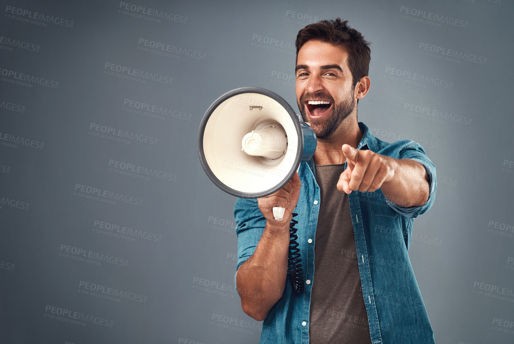 Buy stock photo Studio shot of a handsome young man using a megaphone against a grey background