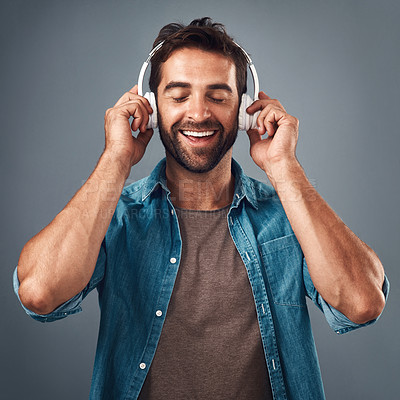 Buy stock photo Studio shot of a handsome young man wearing headphones against a grey background