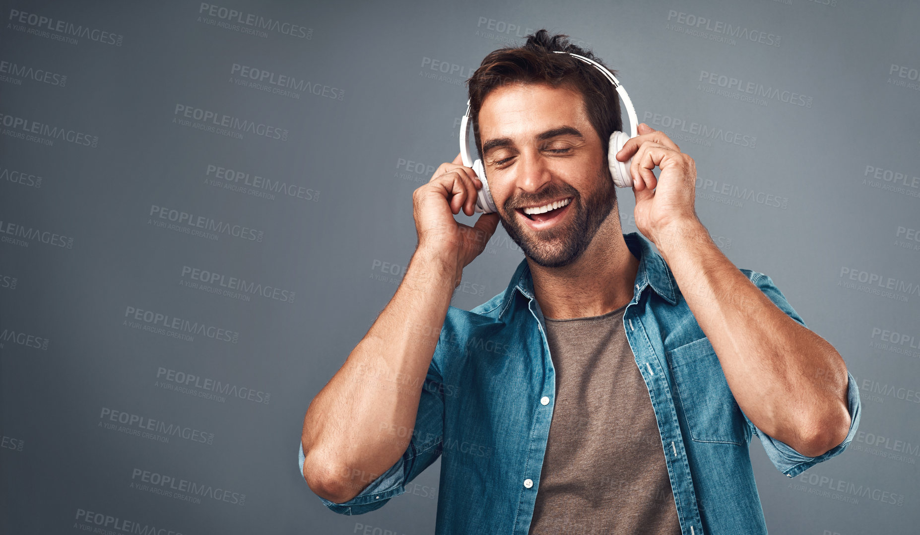 Buy stock photo Studio shot of a handsome young man wearing headphones against a grey background