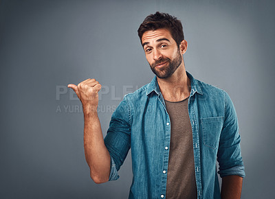 Buy stock photo Studio shot of a handsome young man pointing at copy space against a grey background