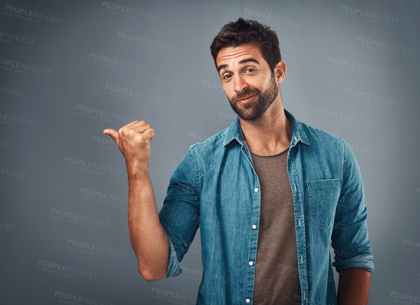 Buy stock photo Studio shot of a handsome young man pointing at copy space against a grey background