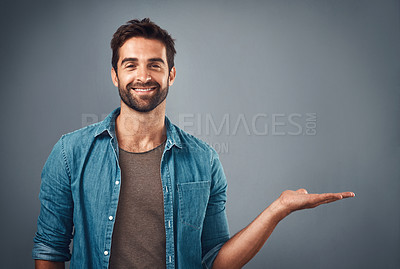 Buy stock photo Studio shot of a handsome young man showing copy space against a grey background