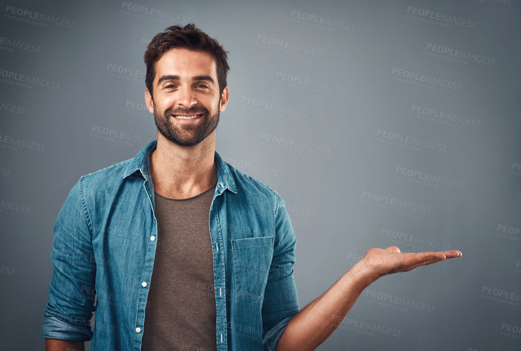 Buy stock photo Happy man, portrait and palm with deal, presentation or advertising in studio on a gray background. Young male person or model with smile and hand out for marketing, choice or offer on mockup space