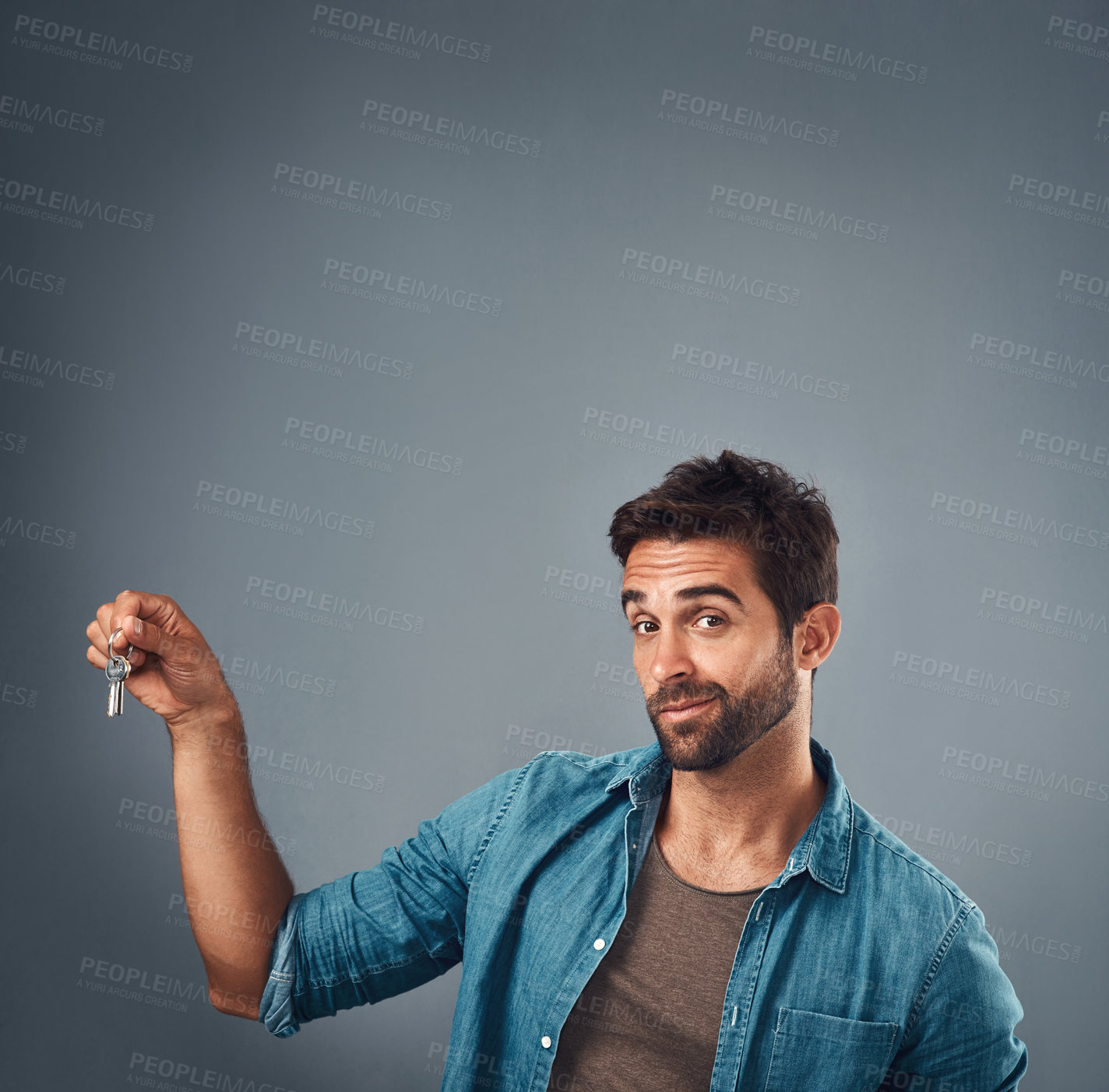 Buy stock photo Studio shot of a handsome young man holding a set of keys against a grey background