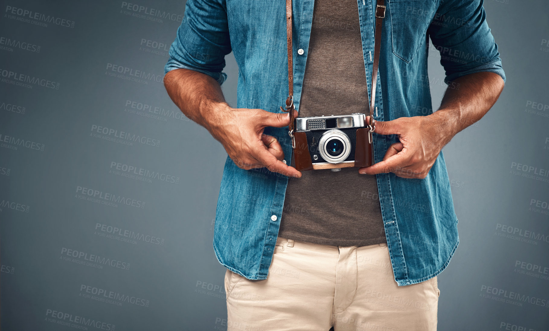 Buy stock photo Cropped studio shot of a young man with a camera around his neck against a grey background