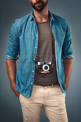 Buy stock photo Cropped studio shot of a young man with a camera around his neck against a grey background